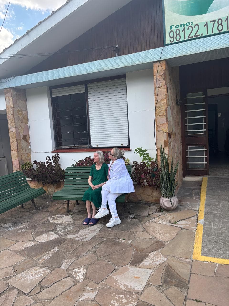 Residente e cuidadora conversando na frente do residencial