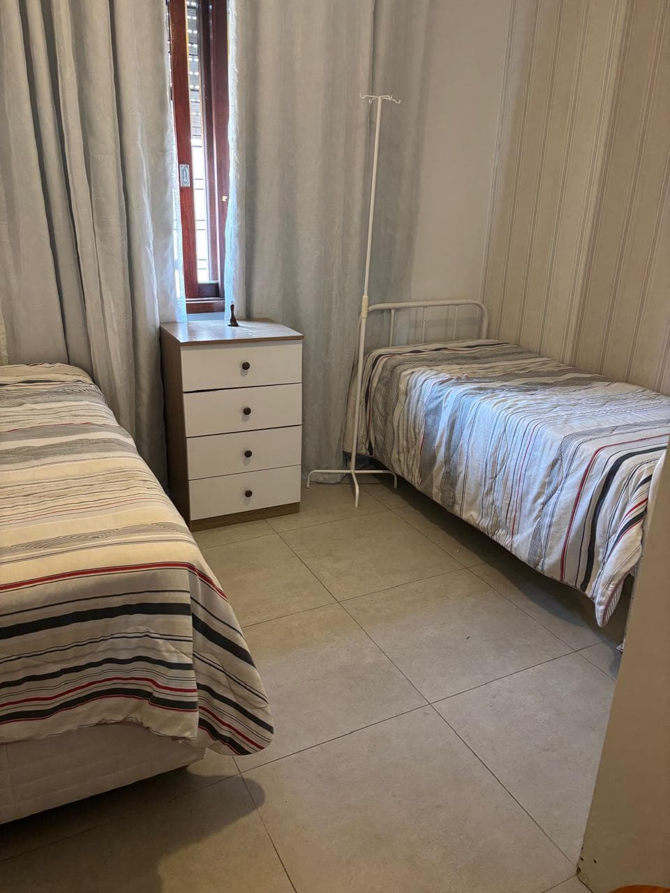 Quarto compartilhado com duas camas e suporte para soro