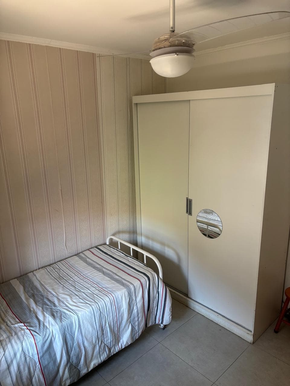 Quarto com cama de solteiro e guarda-roupa com espelho