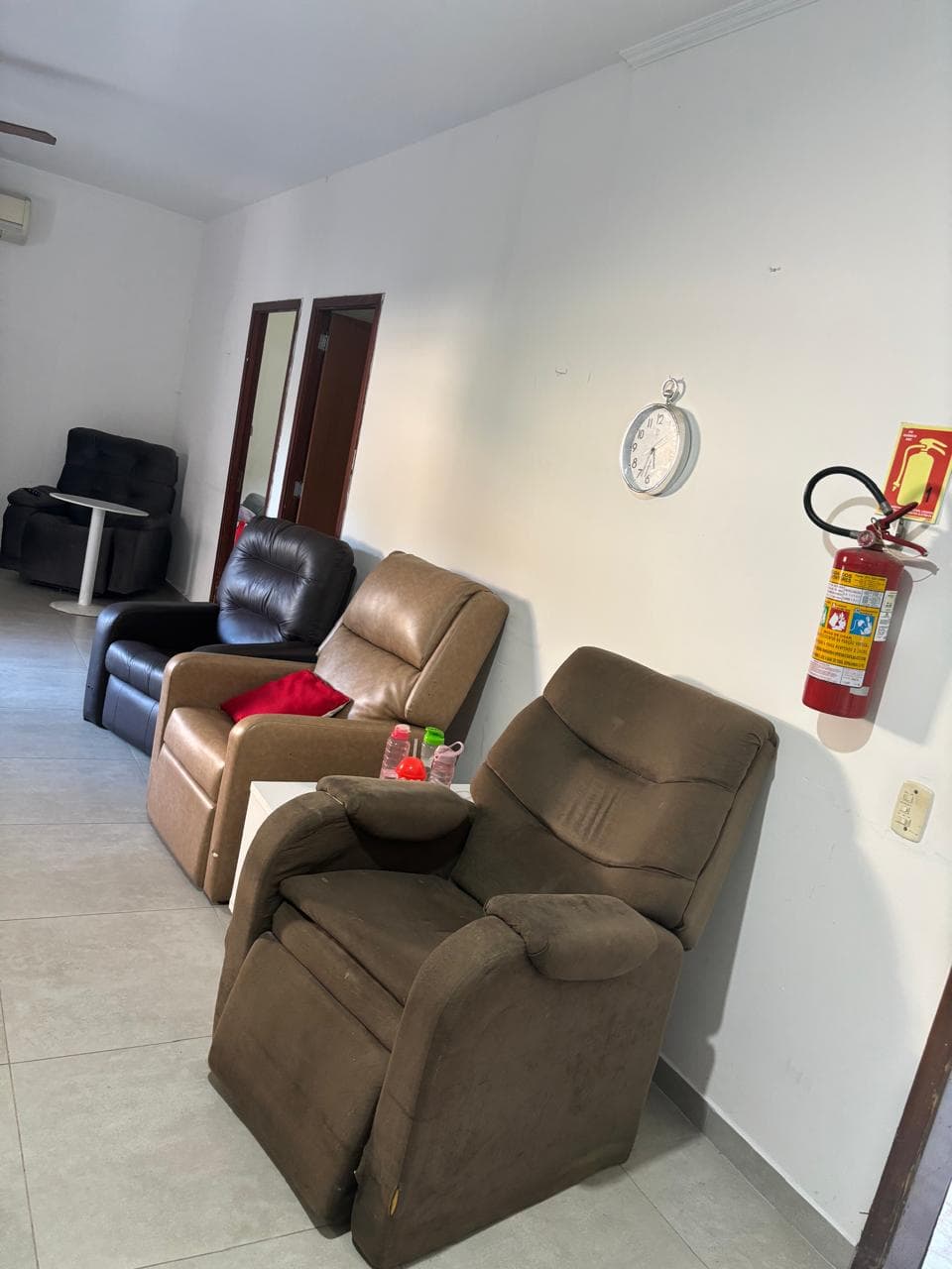 Sala de convivência com poltronas reclináveis e extintor de incêndio