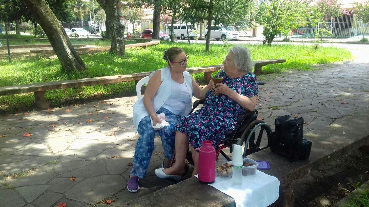 Cuidadora e residente conversando no parque